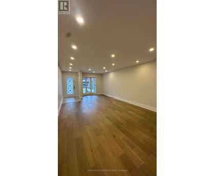 A spacious room with wooden flooring and recessed lighting.