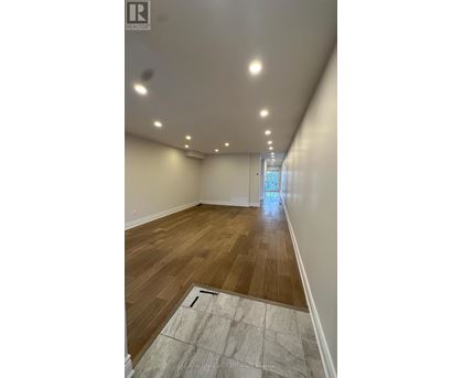 A long, empty hallway with wooden floors and white walls.