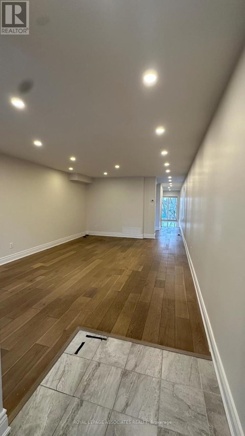 A long, empty hallway with wooden floors and white walls.
