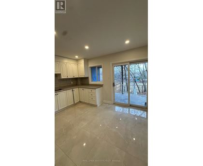 A spacious kitchen with white cabinets and a tiled floor.