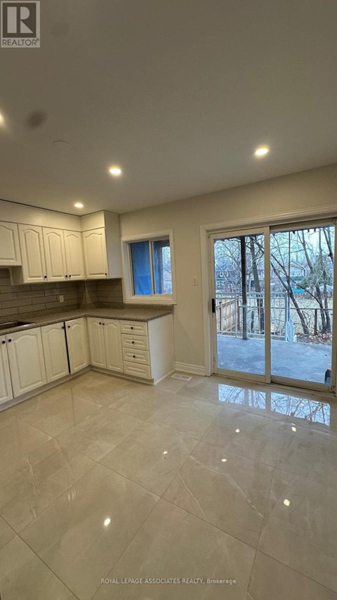 A spacious kitchen with white cabinets and a tiled floor.