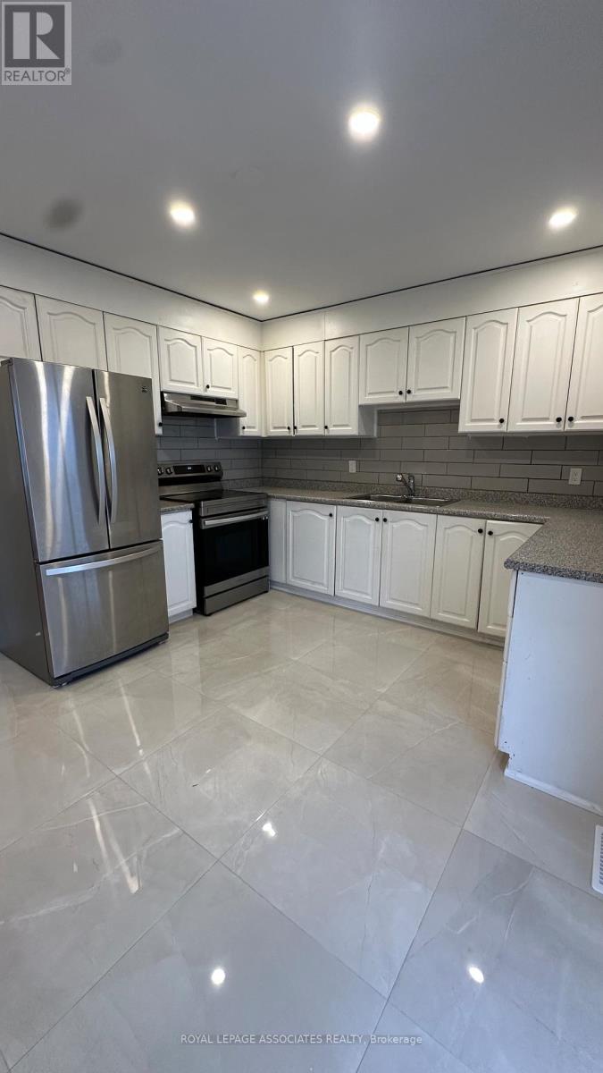 A modern kitchen with white cabinets and a marble floor.