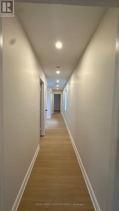 A long hallway with white walls and wood floors.