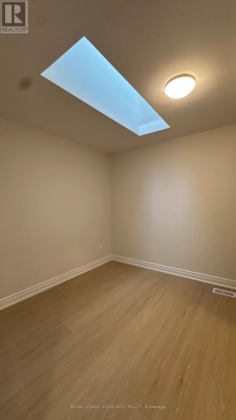 A room with a skylight and wooden flooring.