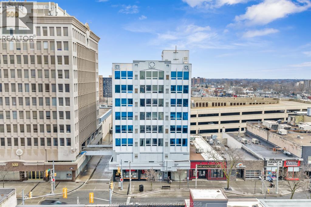 A city street with a tall white building with blue windows in the middle.