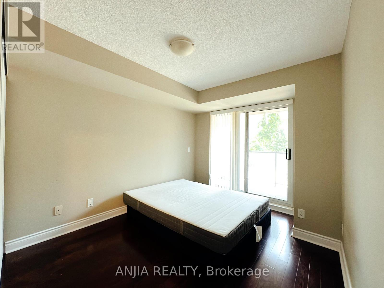 A bedroom with a bed, wooden floors, and a window.