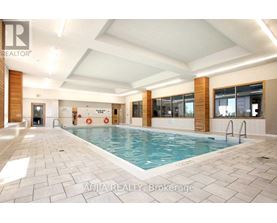 A large indoor swimming pool with a tiled floor and a glass wall on one side.