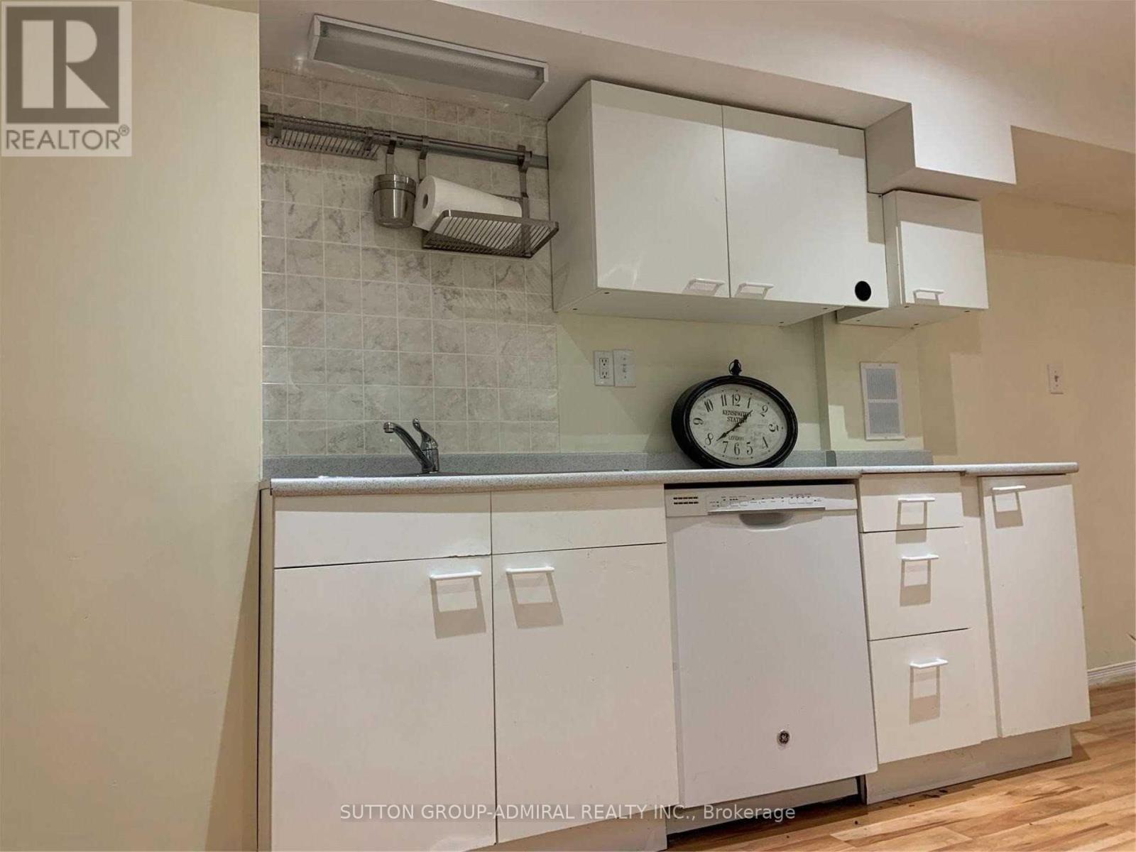 A kitchen with white cabinets and a clock on the counter.