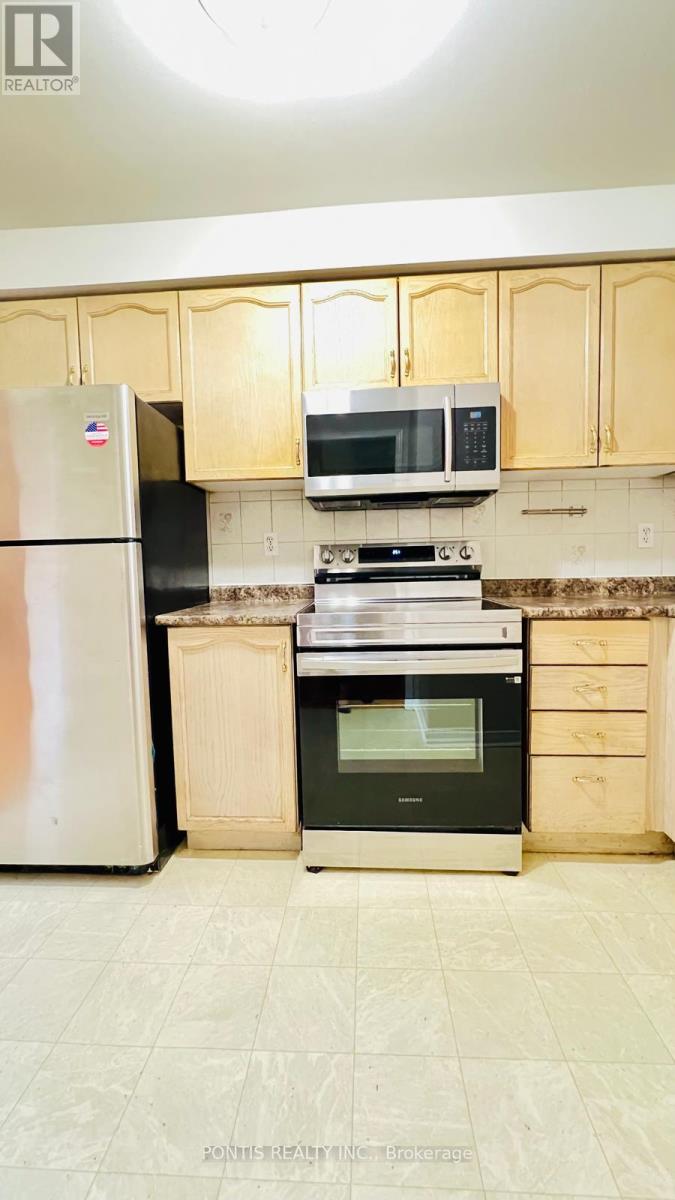 A kitchen with a fridge, microwave, oven and cabinets.