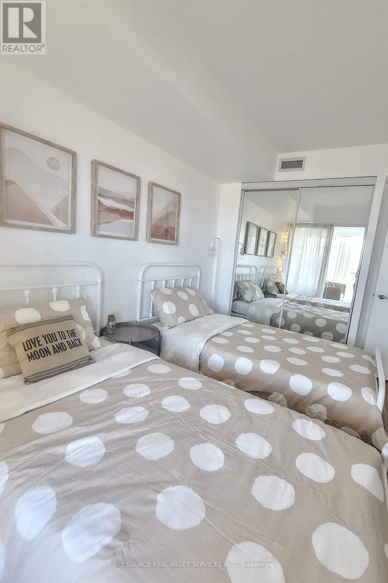 A bedroom with two beds and a mirror.