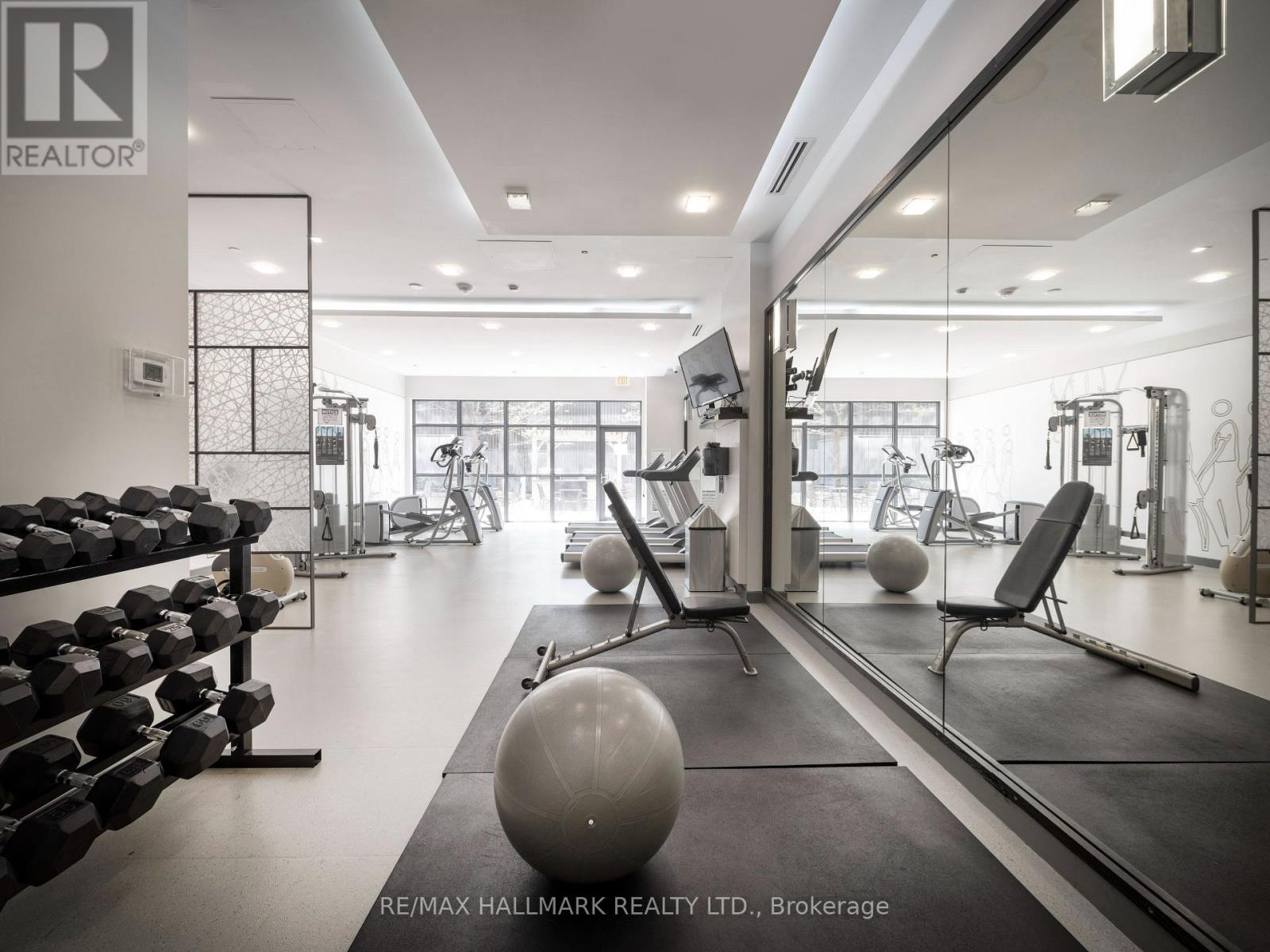 A gym with a variety of equipment including dumbbells, exercise balls, and weight machines.