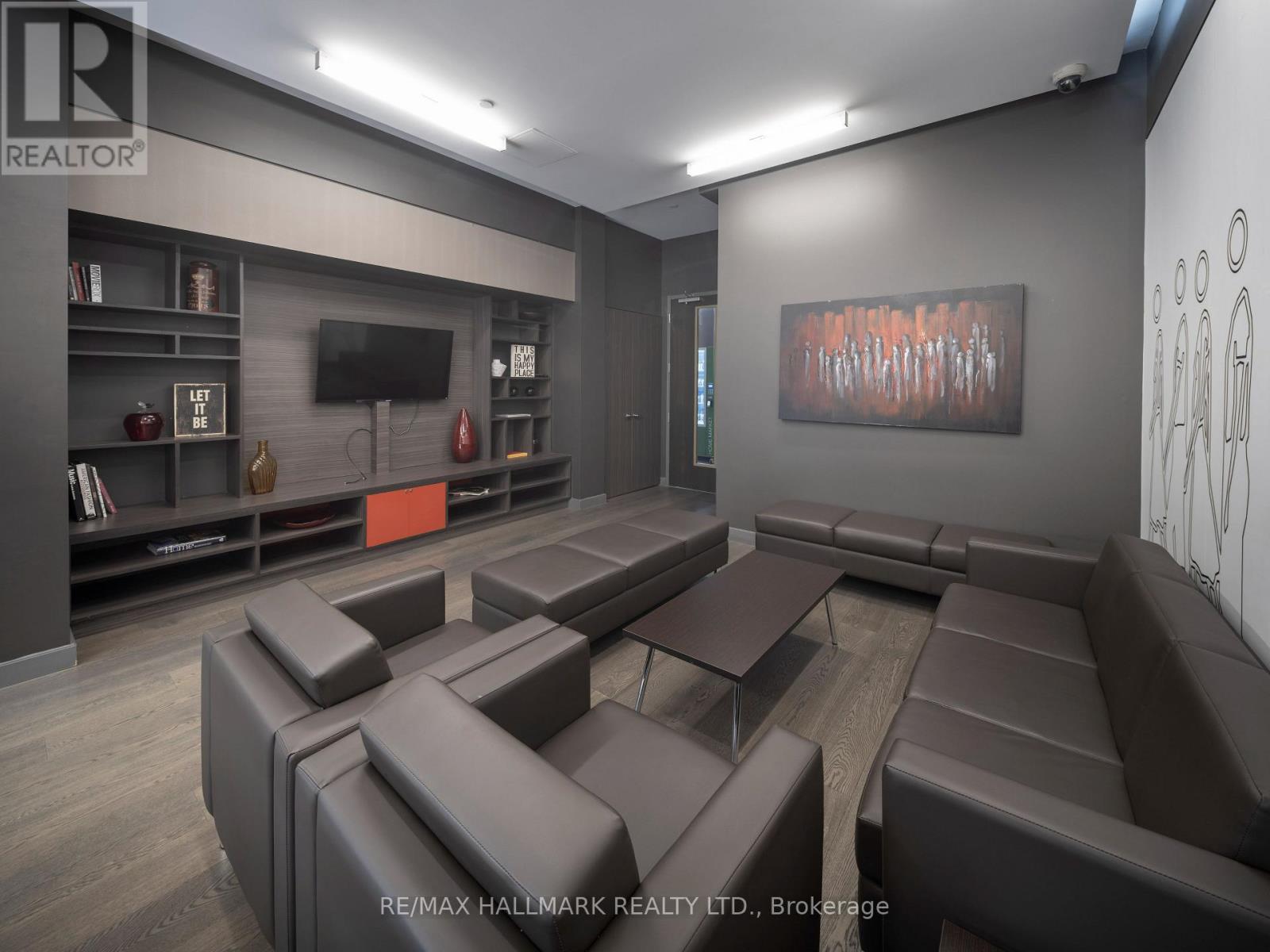 A modern living room with brown leather furniture and a painting on the wall.