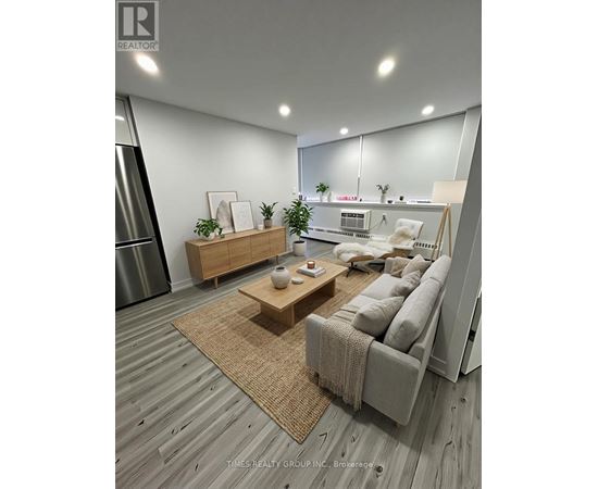 A modern living room with a grey sofa, wooden coffee table, and a large mirror on the wall.