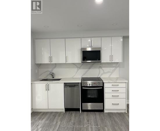 A kitchen with white cabinets and a black microwave.