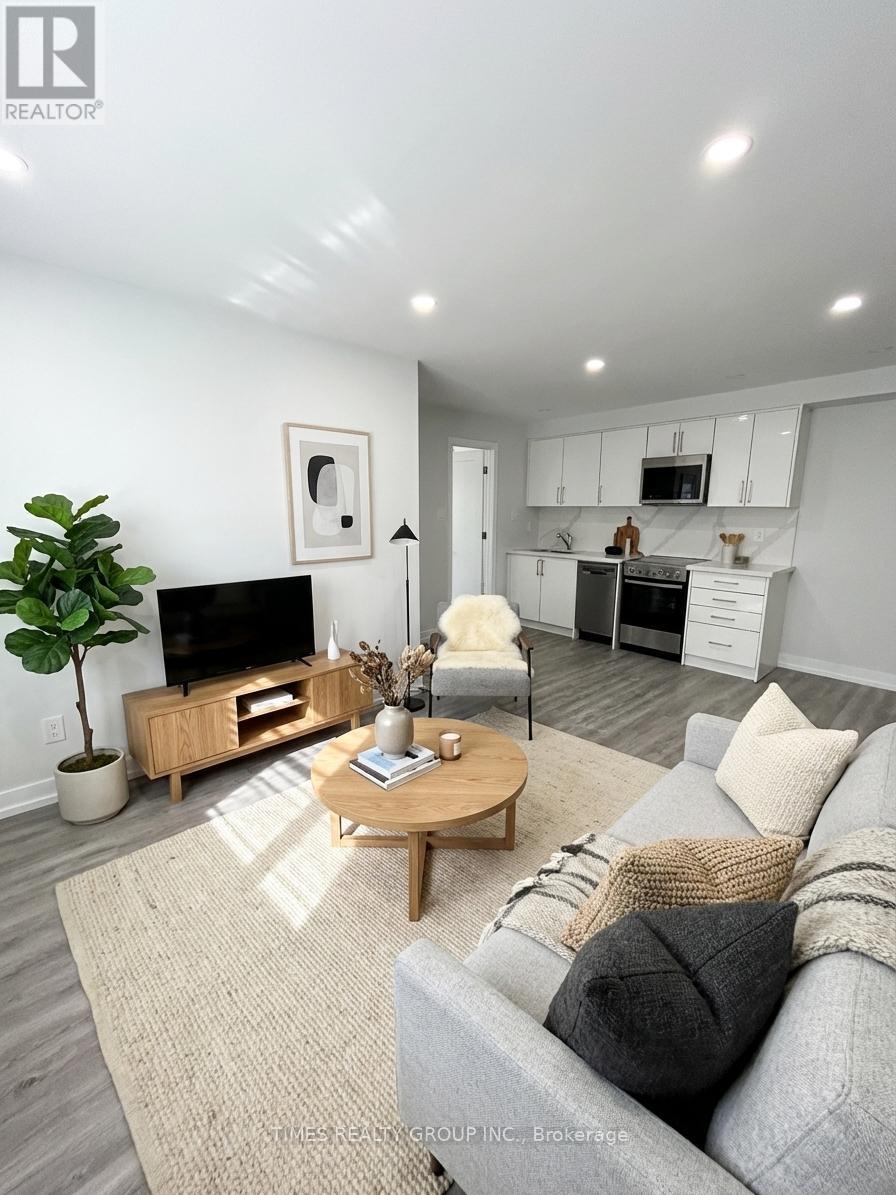 A living room with a grey couch, a wooden coffee table, and a TV on the wall.