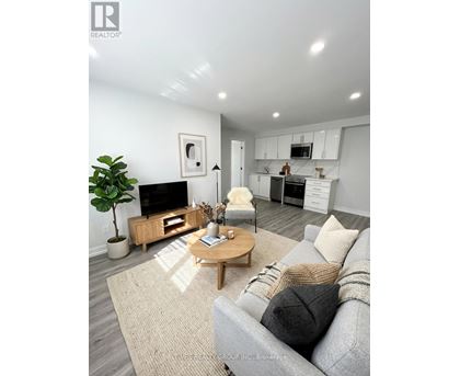 A living room with a grey couch, a wooden coffee table, and a TV on the wall.