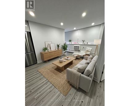 A modern living room with a grey sofa, wooden coffee table, and a large mirror on the wall.