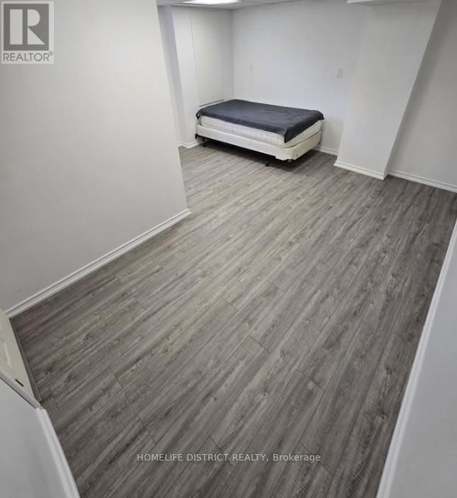 A bedroom with a bed and wooden flooring.