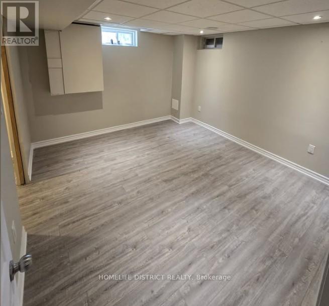 A room with wooden flooring and a door on the left.