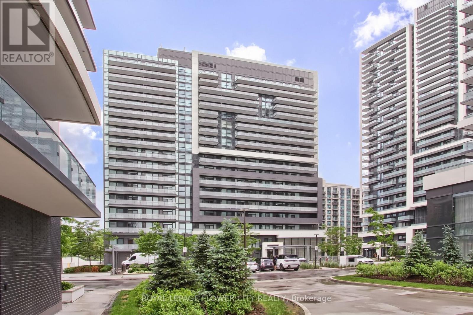 A modern building with a glass facade stands tall among other buildings.