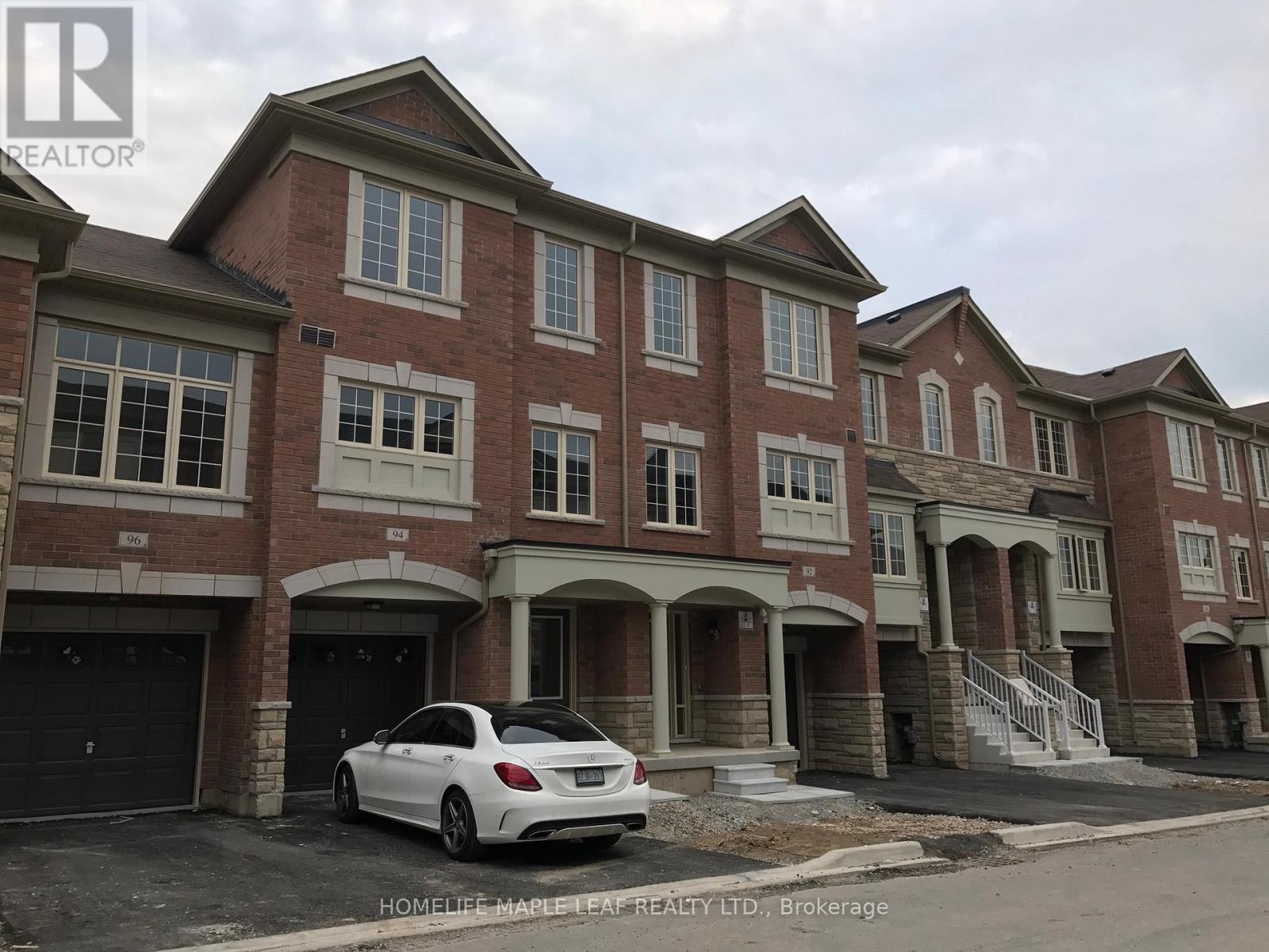 A white car is parked in front of a brick building.