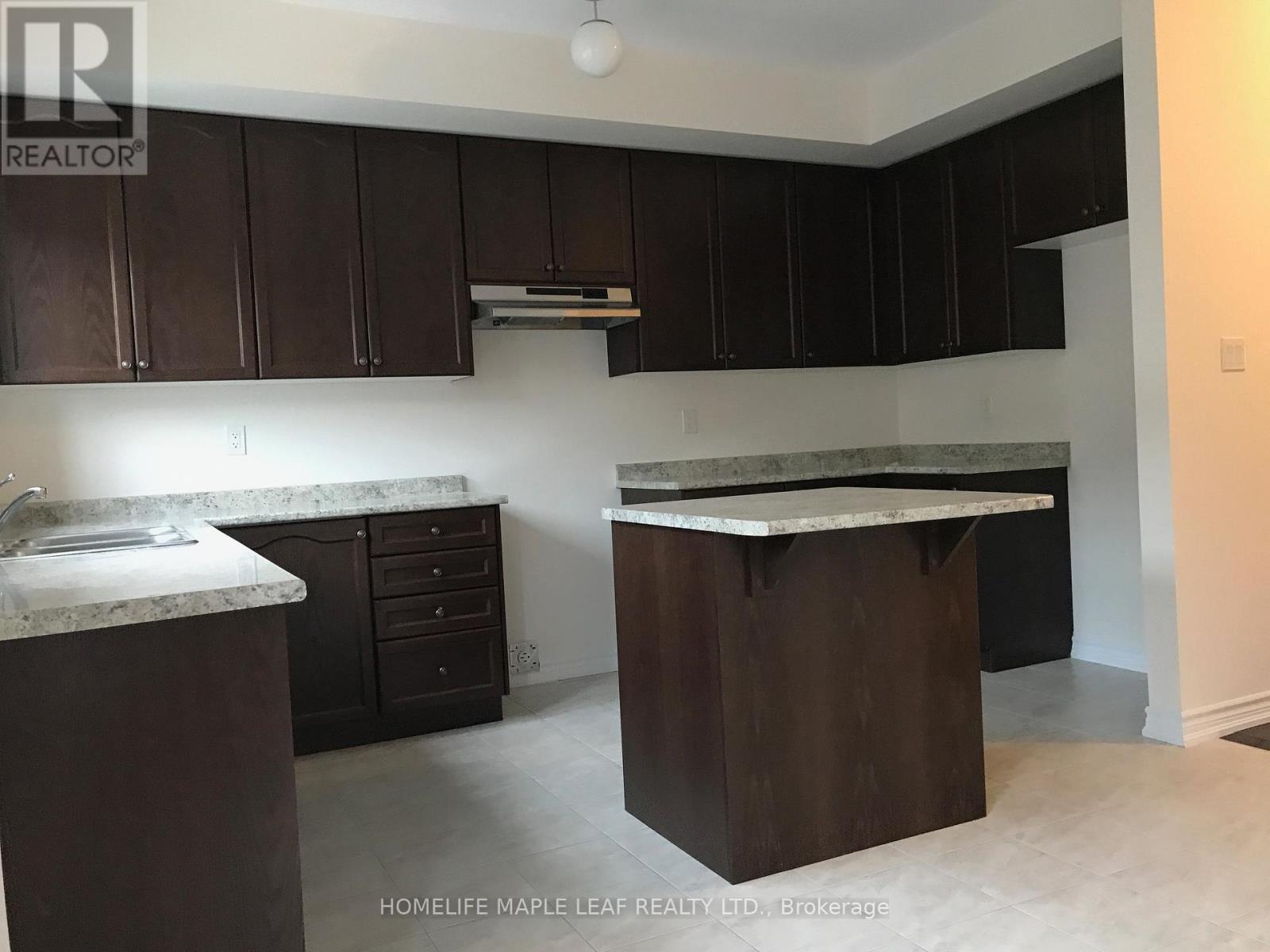 A kitchen with dark brown cabinets and a marble countertop.