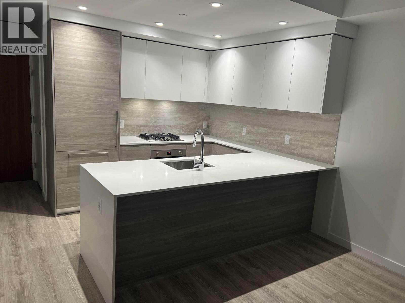 A modern kitchen with a white countertop and a sink.