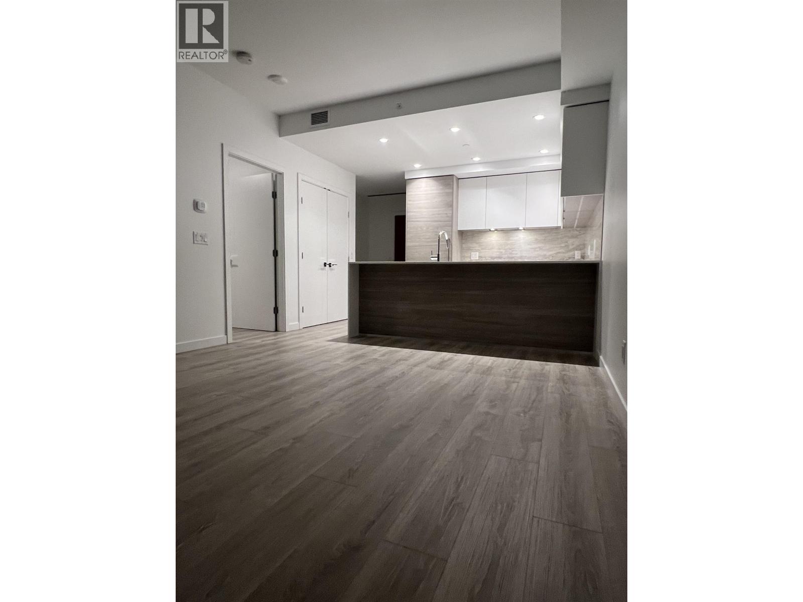 A room with a wooden floor and a counter in the background.