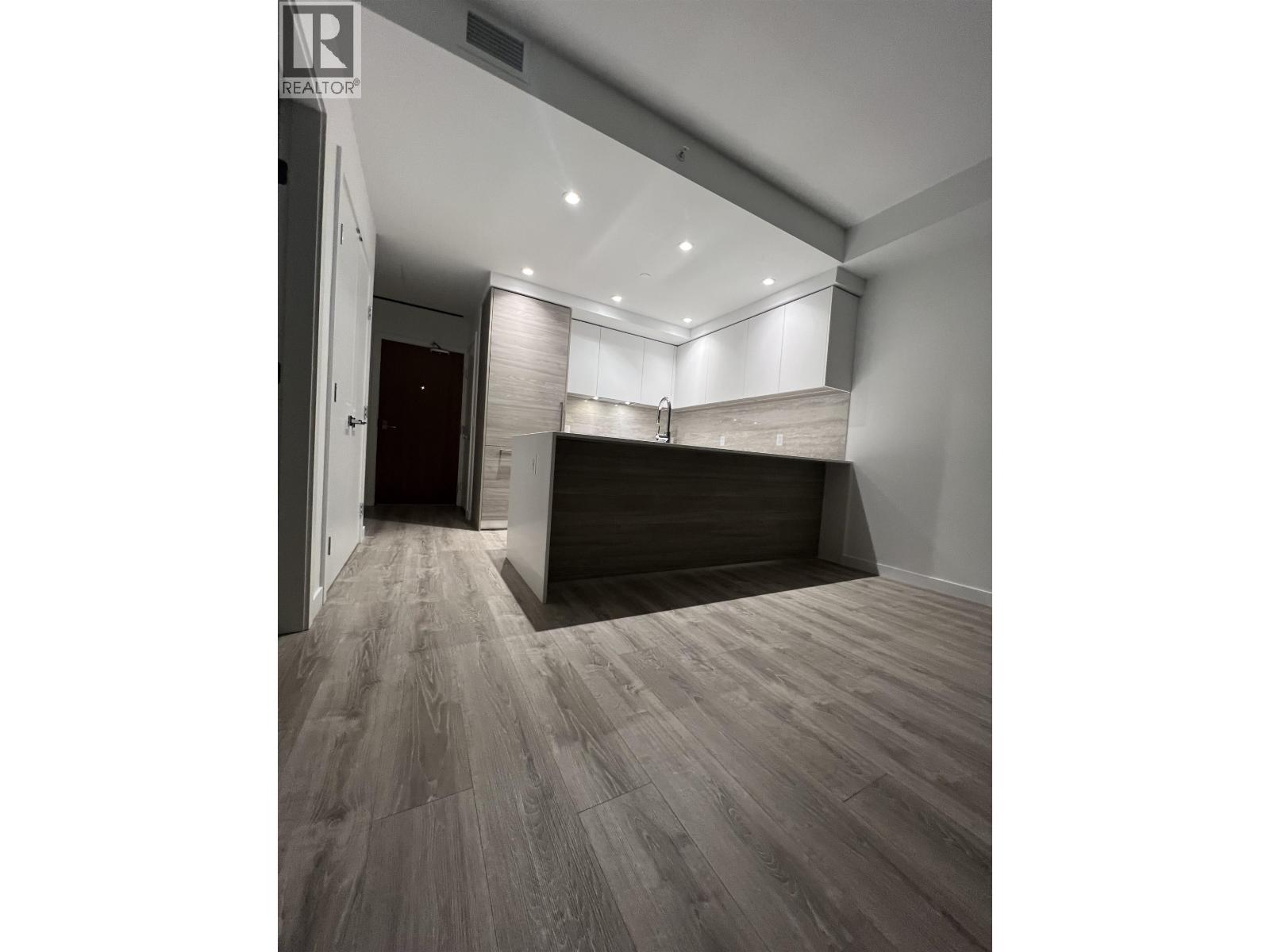 A room with a wooden floor and a white ceiling with a light on it.