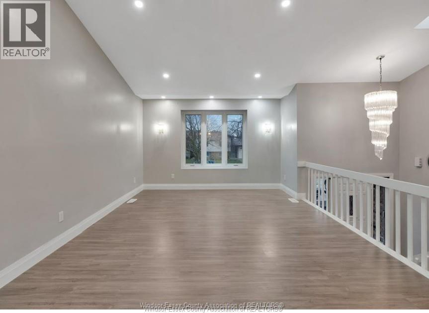 A spacious room with wooden flooring and white railings.
