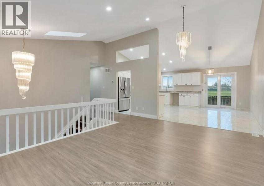 A spacious living room with a staircase and a chandelier.