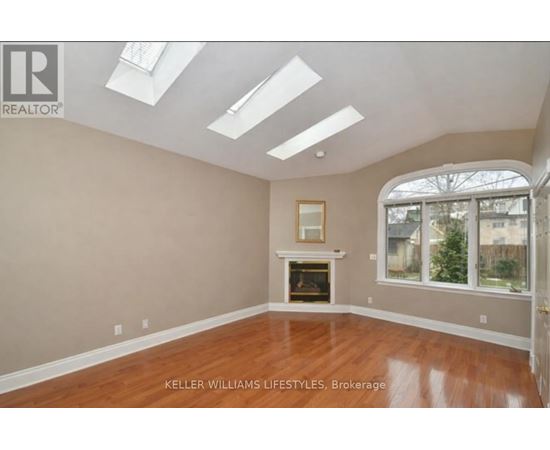 A spacious room with a fireplace and skylights.