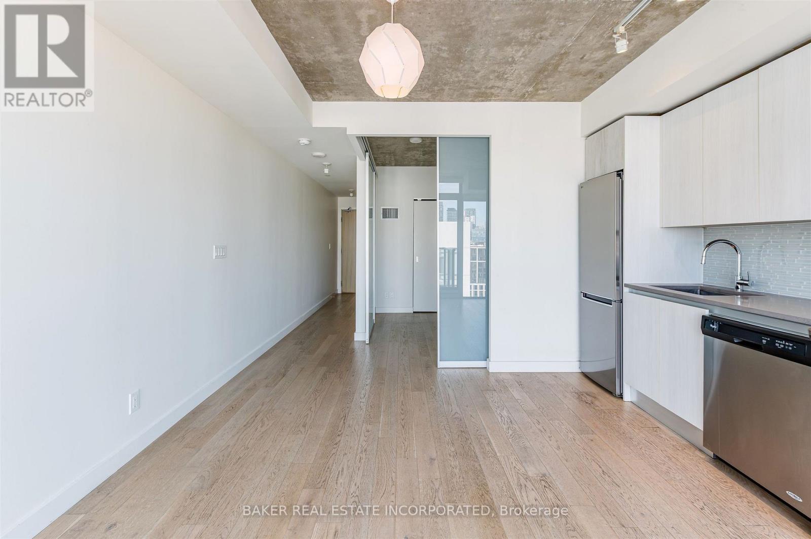 A kitchen with white cabinets and a wooden floor.