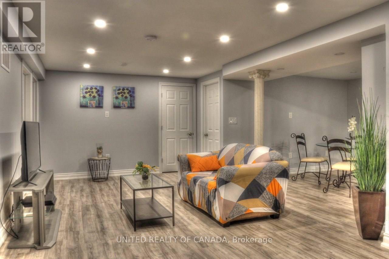 A living room with a couch, chairs, and a television.