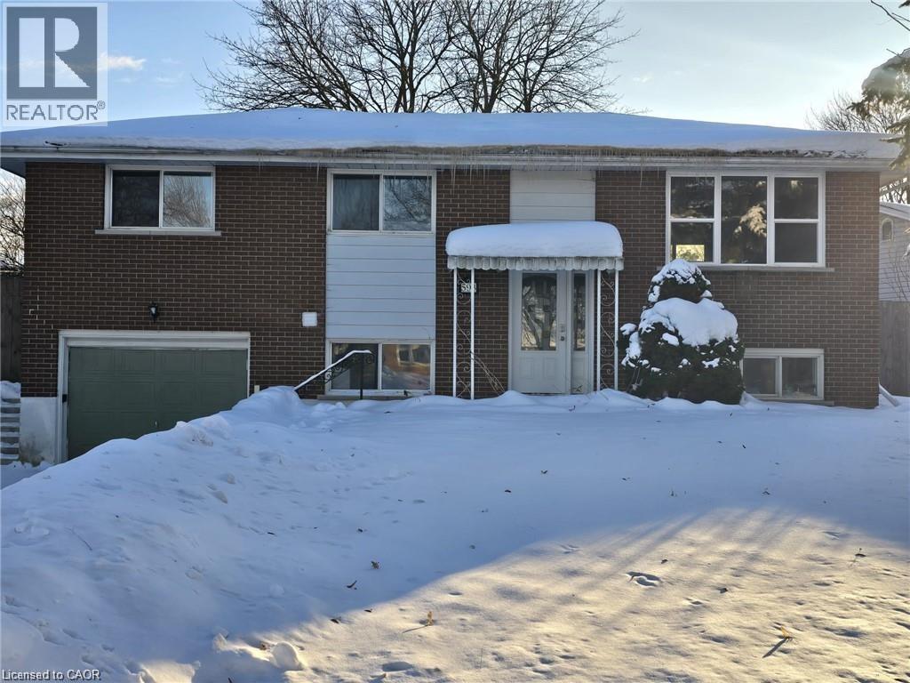 A house with a snow-covered front yard and a tree in the front yard.
