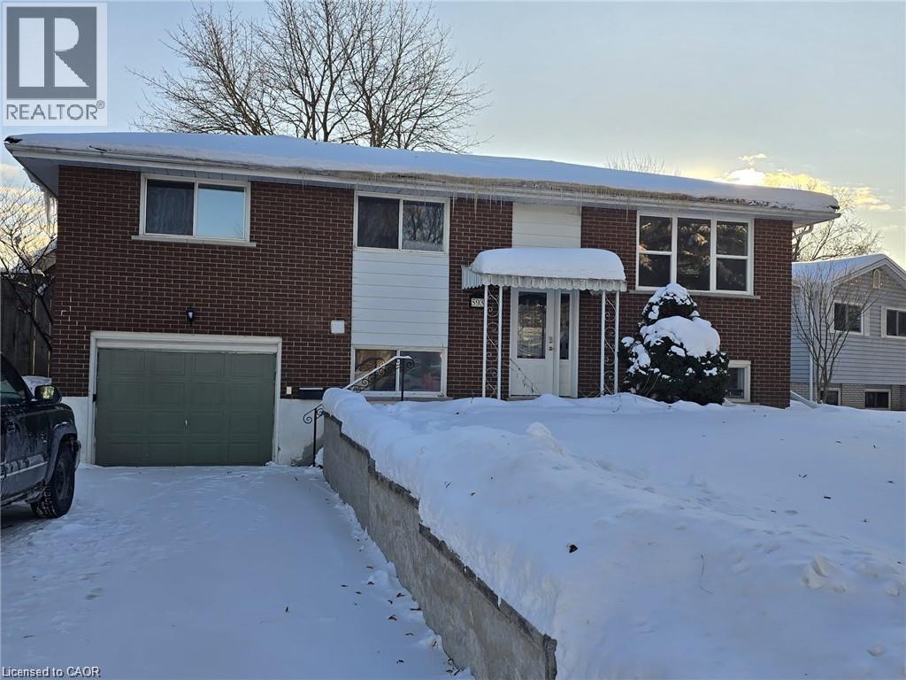 A house with a garage and a tree covered in snow.