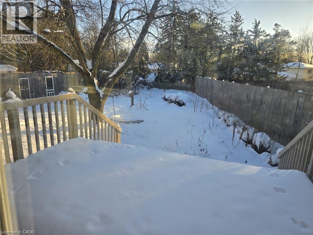 A snow-covered backyard with a deck and trees.