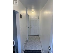 A hallway with a brokerage sign on the floor.