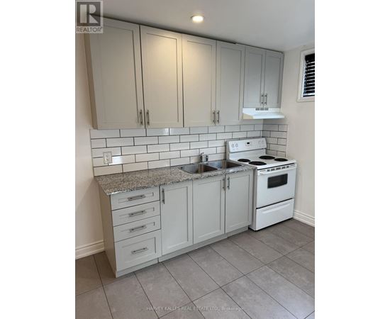 A kitchen with white cabinets and a white stove top oven.