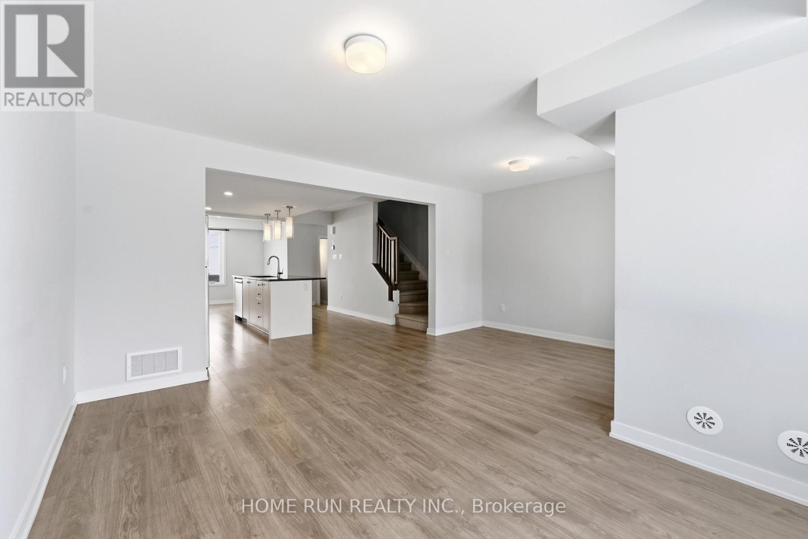 A spacious room with wooden flooring and white walls.
