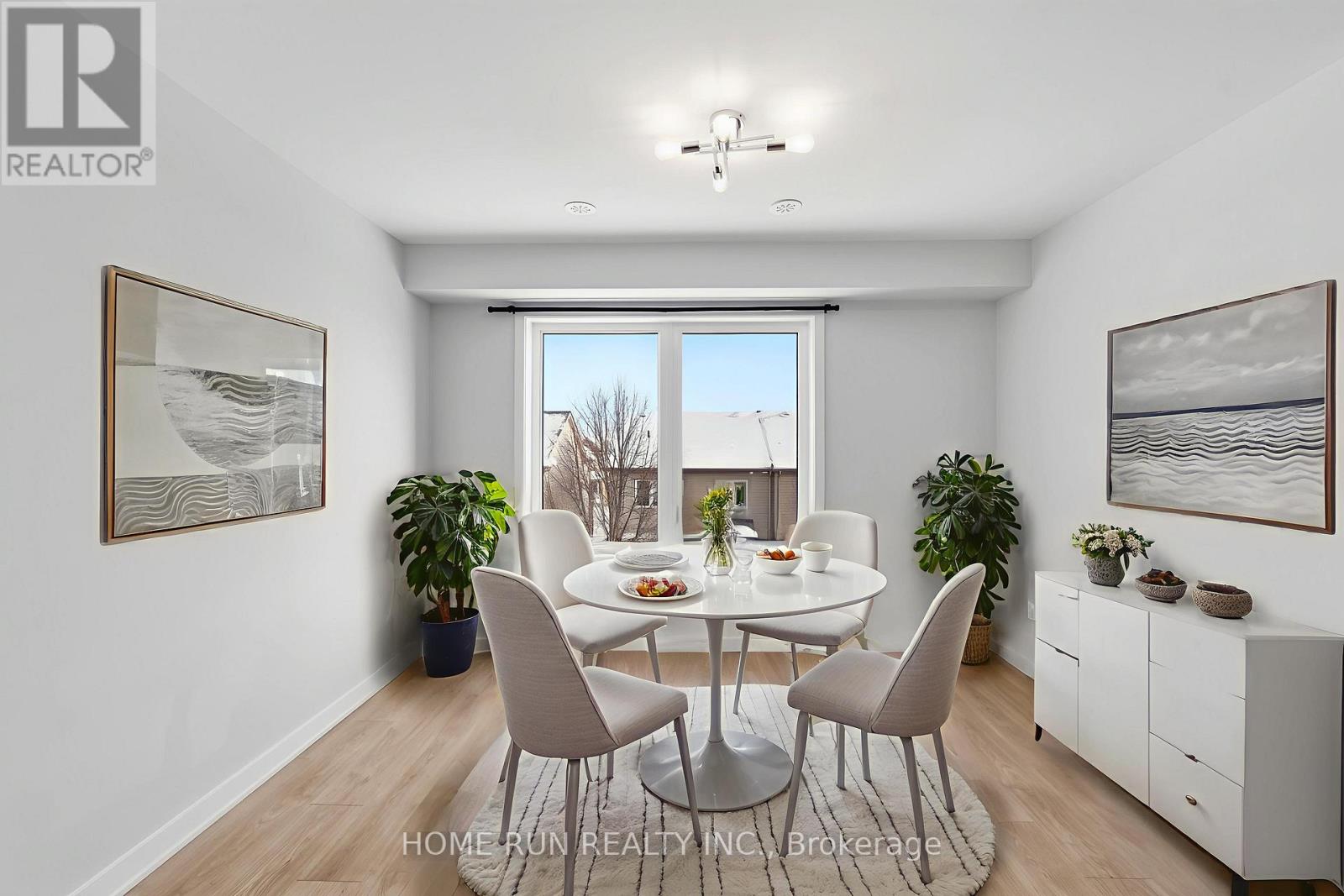 A dining room with a table set for four and a view of a snowy landscape outside the window.