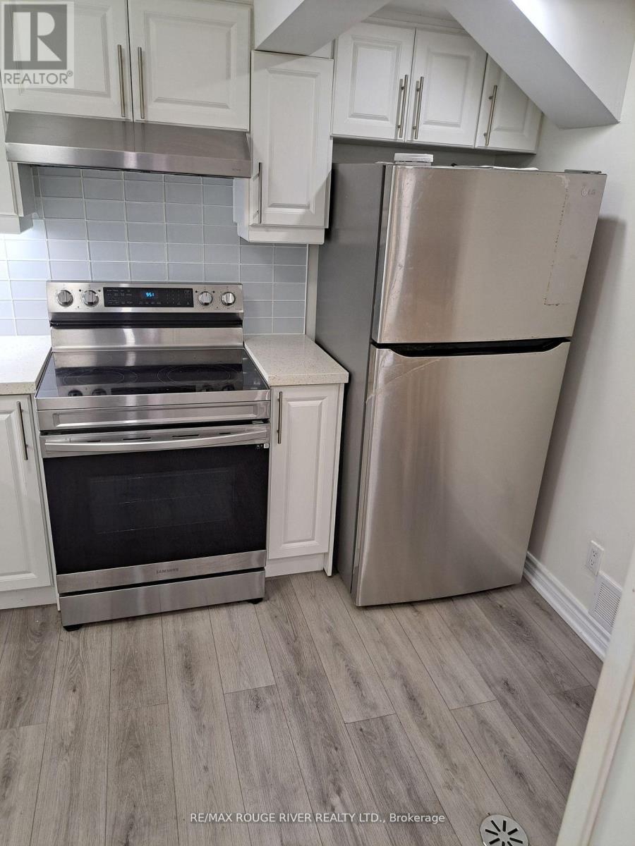 A stainless steel refrigerator stands next to a stove in a kitchen.