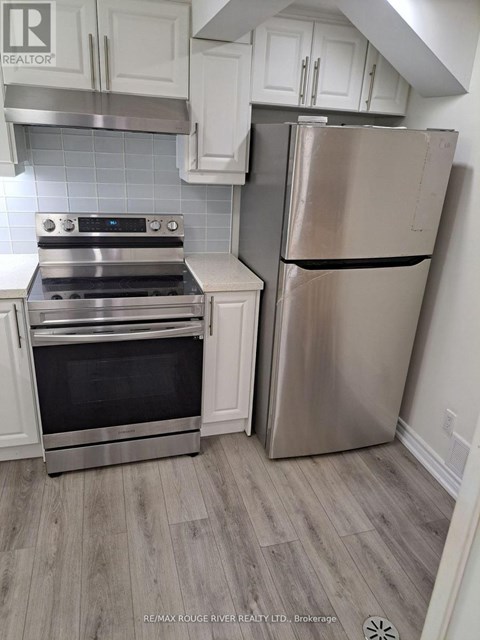 A stainless steel refrigerator stands next to a stove in a kitchen.