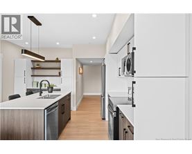 A modern kitchen with white cabinets and a wooden floor.