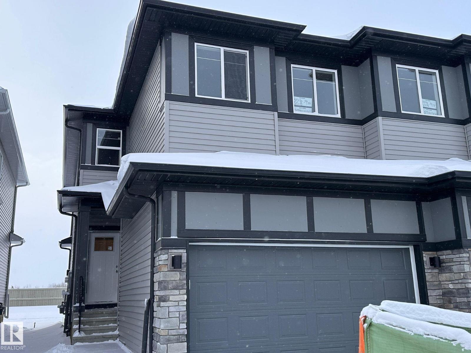 A house with a grey garage door and a white door.