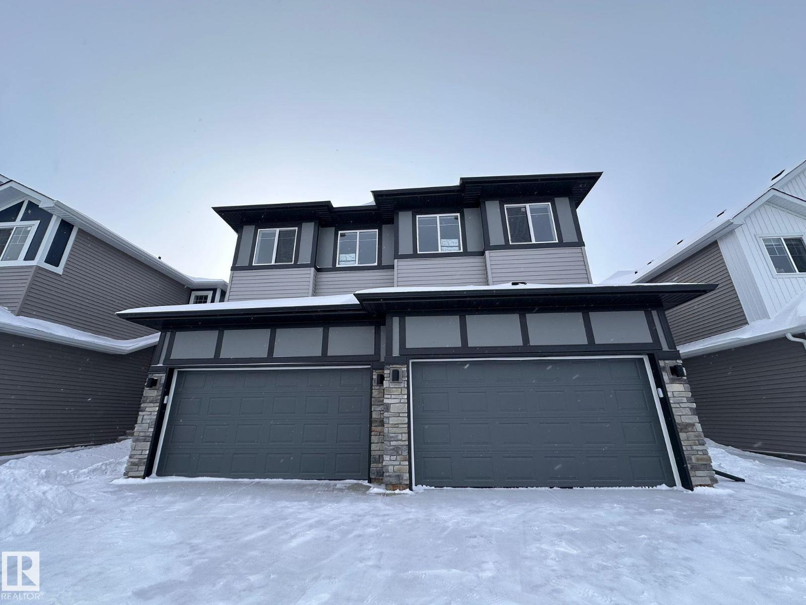 A house with a grey garage door in the snow.