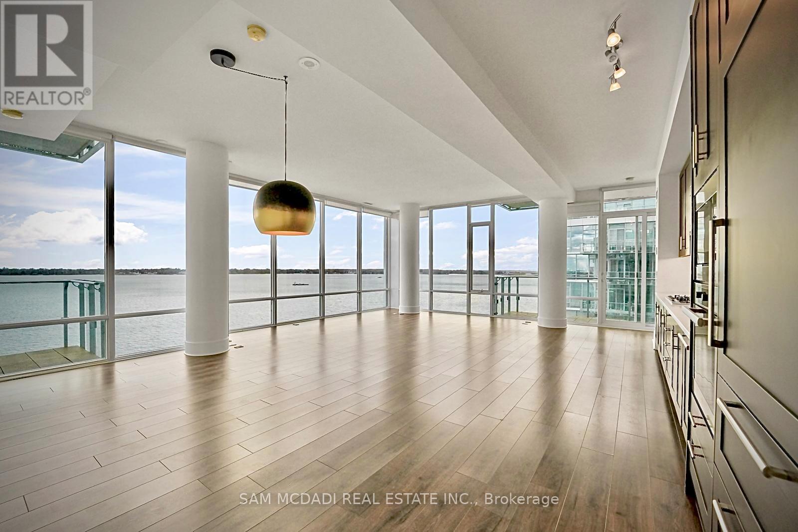 A spacious room with wooden floors and a large window overlooking the water.