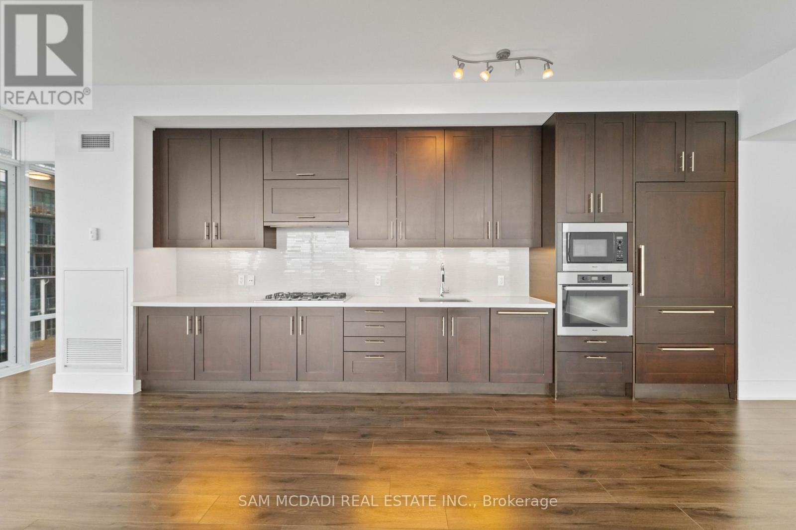 A modern kitchen with wood floors and cabinets.