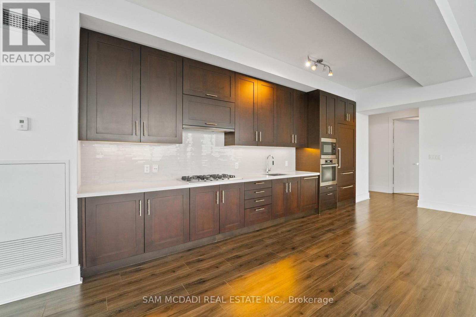 A kitchen with dark wood cabinets and a white counter top.