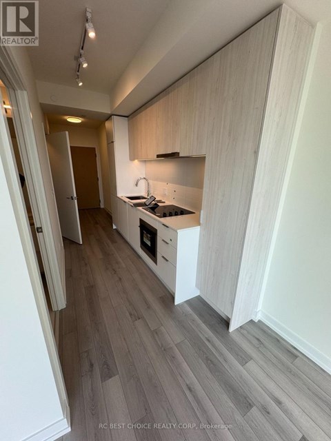 A kitchen with white cabinets and a wooden floor.